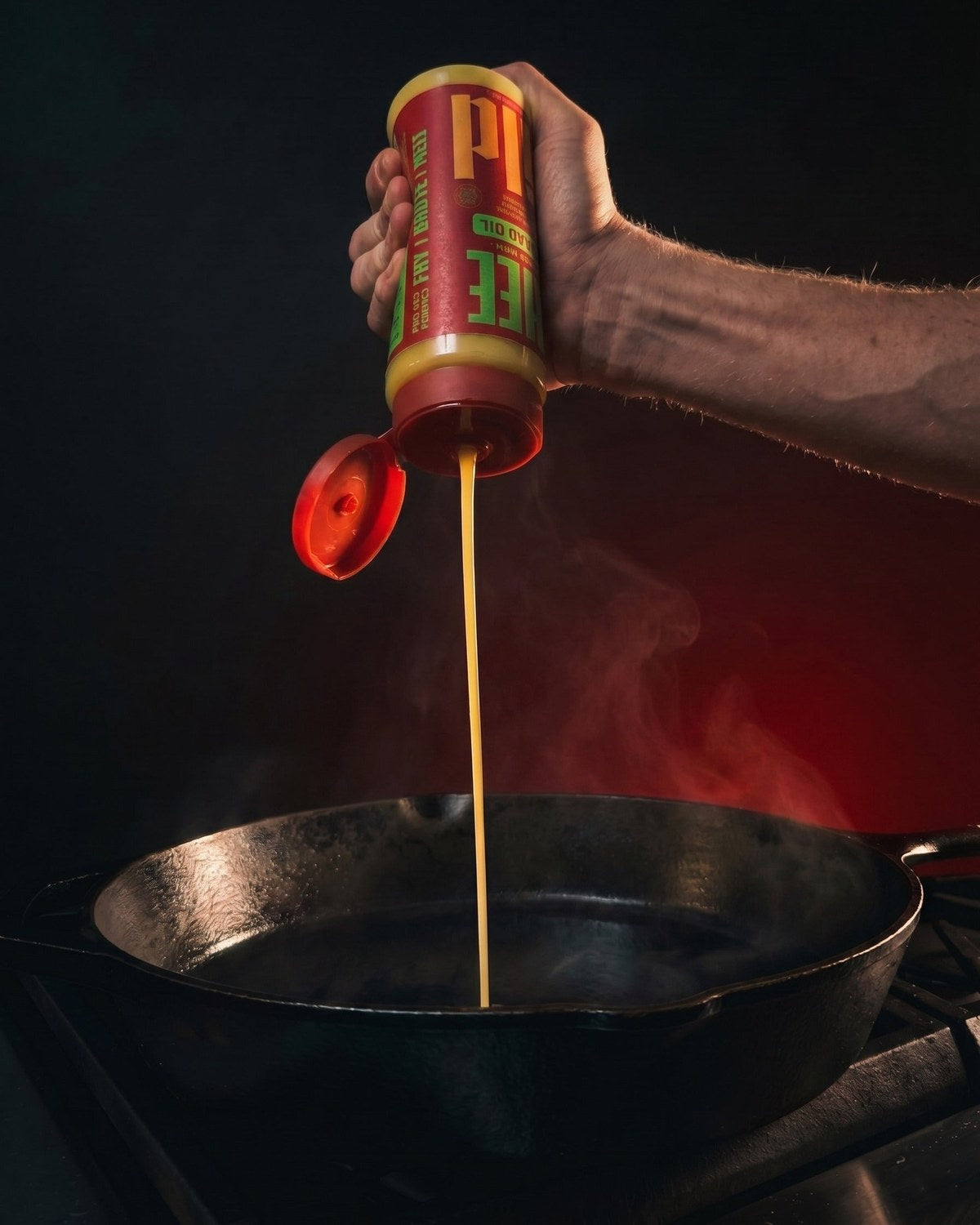A hand squeezing GILD Ghee into a hot cast-iron skillet, steam rising