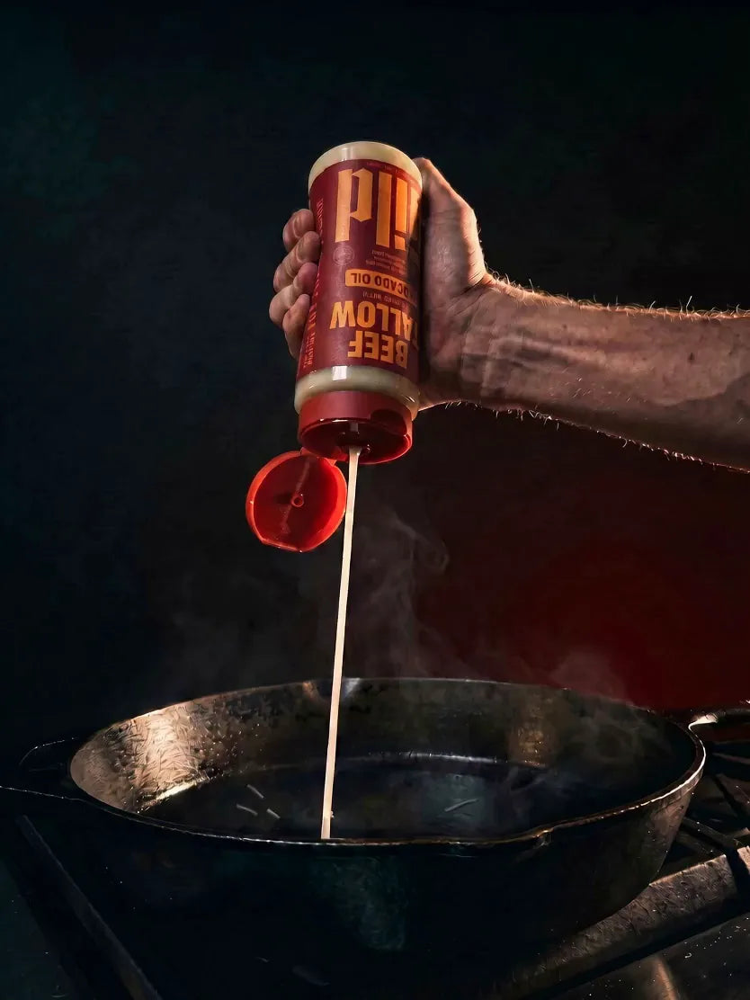 GILD Beef Tallow squeezed in a creamy ribbon into a hot cast-iron pan